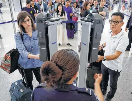  ?? Michael Wyke photos ?? Customs Officer Charmaine Guillory is ready to assist flyers as they use facial recognitio­n kiosks at Bush Interconti­nental.