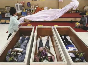  ??  ?? Devotees lie down and pray inside coffins to trick death and improve their luck at a temple in Bangkok, Thailand.