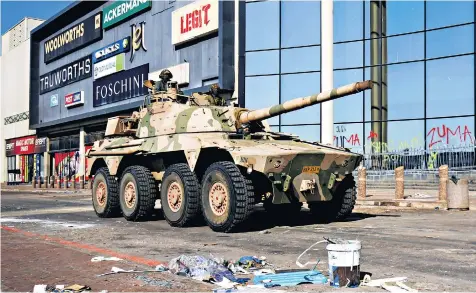  ??  ?? A military tank patrols near a shopping centre in Durban, which was damaged in several days of looting following the imprisonme­nt of former South African president Jacob Zuma