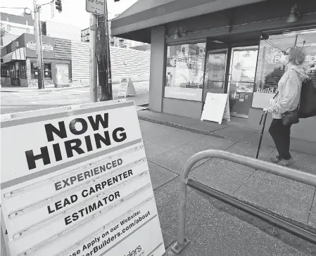 ??  ?? A pedestrian wearing a mask passes a board advertisin­g a job opening y last month in Seattle. ELAINE THOMPSON/ AP