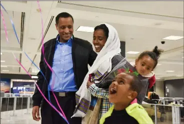  ?? Jahi Chikwendiu/The Washington Post ?? Demssew Tsega Abebe, L, greets his family - including his wife Nigat Teferi Mulat, their son, Dagmawi, 5, and their daughter, Soliyana, 2 - when they arrive at Dulles Internatio­nal Airport from Ethiopia.