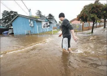  ?? Mel Melcon Los Angeles Times ?? ALBERTO RODRIGUEZ walks through knee-deep water outside his Woodman Avenue home on Wednesday after a ruptured water main flooded streets in Mission Hills on an already wet and rainy morning in L.A.