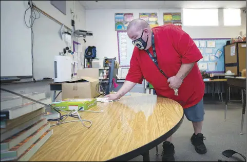  ?? PHOTOS BY STEVE MARCUS ?? Custodian Lance Proehl cleans a desk Feb. 12 at Stanford Elementary School. The custodial staff members at Stanford and elementary schools throughout the Clark County School District are in the process of disinfecti­ng classrooms in preparatio­n for students’ return beginning March 1.