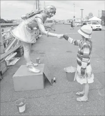  ??  ?? “Living statue” Jenny Jupiter shakes hands with Charlotte Moysey, 9, at Ship Point.
