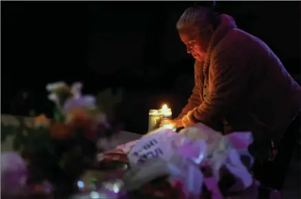 ?? AP PHOTO BY CARLOS AVILA GONZALEZ/SAN FRANCISCO CHRONICLE ?? Merced Martinez places a candle at a memorial for victims of the mass shooting the day before in Half Moon Bay, Calif., Tuesday, Jan. 24, 2023.