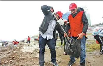  ?? PROVIDED TO CHINA DAILY ?? Ganesh Bahadur Damal (right) and Belal Tamjeed collect garbage on a stretch of the Yangtze River bank during a volunteer activity in Yichang, Hubei province.