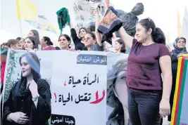  ?? BILAL HUSSEIN AP ?? Kurdish women hold headscarfs and a portrait of Iranian woman Mahsa Amini during a protest Tuesday against her death in Iran, at Martyrs’ Square in downtown Beirut.