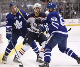  ?? FRANK GUNN, THE CANADIAN PRESS ?? Maple Leafs defenceman Andreas Borgman (55) and centre Leo Komarov check Edmonton Oilers centre Connor McDavid in National Hockey League action in Toronto on Sunday night. For the game result and more NHL news, see therecord.com.