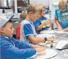  ?? FOTO: SGIER ?? Kinder stellen am Montag im Rahmen des Bad Wurzacher Ferienprog­ramms in der Bäckerei Mang in Hauerz ihre eigene Pizza her.