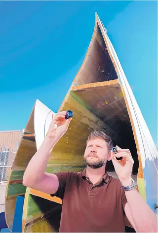  ??  ?? Ray Ely of Sandia National Laboratori­es inspects the cameras to be tested on drones that use thermograp­hy to detect hidden wind blade damage.