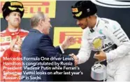  ??  ?? Mercedes Formula One driver Lewis Hamilton is congratula­ted by Russia President Vladimir Putin while Ferrari’s Sebastian Vettel looks on after last year’s Russian GP in Sochi.