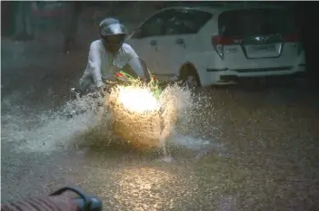  ?? —GANDHI ?? A man on a motorcycle rides through a flooded street at Bagh Lingampall­y on Wednesday.