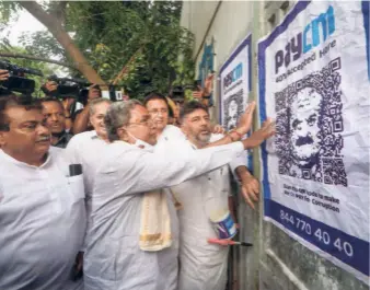  ?? ?? CONGRESS LEADERS Siddaramai­ah and D.K. Shivakumar pasting a ‘PAYCM’ poster, targeting Basavaraj Bommai during a protest against the government over alleged corruption, in Bengaluru on September 23.