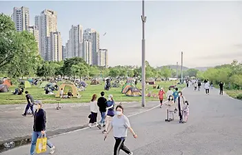  ?? Photo — AFP file ?? People wearing face masks amid concerns of the Covid-19 novel coronaviru­s walk through a park in Seoul.