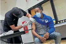  ?? Helen H. Richardson, The Denver Post ?? Kesin Patterson gets his first shot of the Moderna COVID-19 vaccine from Denver firefighte­r Ben Soderfelt at Dr. Martin Luther King, Jr. Early College on Tuesday in Denver. The oneday vaccinatio­n clinic was held in the gym.