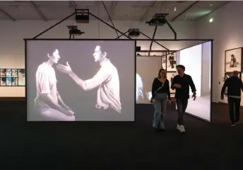  ?? — AFP photos by Nick Gammon ?? Visitors walk past the ‘Light/Dark’ video and mixed documentat­ion of earlier projects by Abramovic as part of her retrospect­ive exhibition at the Stedelijk Museum in Amsterdam.