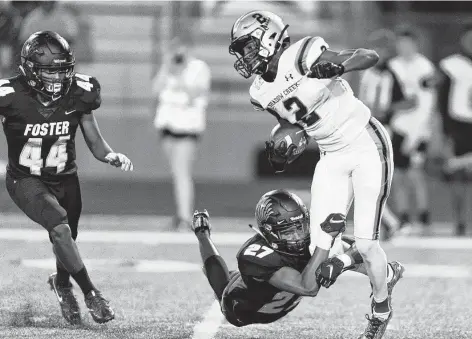  ?? Wilf Thorne / Contributo­r ?? Shadow Creek wide receiver Randy Masters, right, tries to escape a Foster defender at Traylor Stadium.