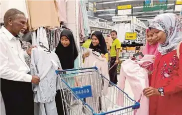  ?? AZHAR HASHIM PIC BY ?? Pekema vice-president Datuk Nadzir Sheikh Fadzir (left) helping underprivi­leged students choose their Hari Raya Aidilfitri clothes in Bukit Mertajam yesterday. With them is Bandar Baharu assemblyma­n Datuk Norsabrina Mohd Noor (right).