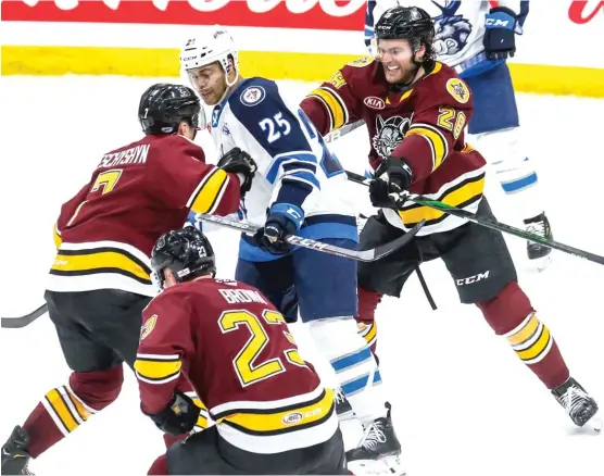  ?? MANITOBA MOOSE ?? Wolves defenseman Jake Bischoff (28) and center Jake Leschyshyn (7) try to clear out Moose center C.J. Suess (25) from in front of the net Thursday.