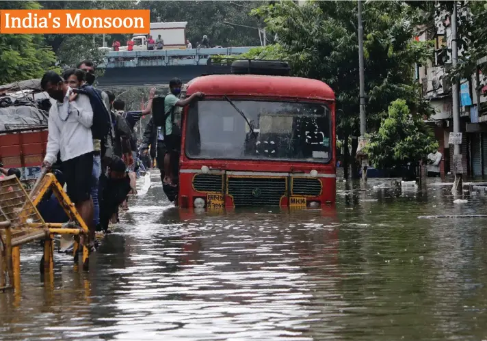  ?? Photo: AP ?? A man holds on to a bus that abandoned the trip as he tries to cross a water-logged street after heavy rain in Mumbai, India, yesterday. India's monsoon season runs from June to September.