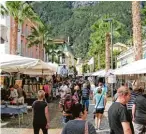  ??  ?? Zur Marktzeit bummeln zahlreiche Besucher durch die Altstadt von Riva und genießen das bunte Treiben.