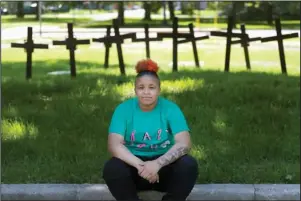  ?? The Associated Press ?? CHICAGO: Sagia Mitchell sits amid crosses outside her high school, North Lawndale College Preparator­y High School, in Chicago on May 30. At the school, she was a Peace Warrior, helping calm conflicts. Her fellow Peace Warriors placed the crosses at her school in 2018, after they carried them in a school walkout to protest gun violence and honor the dead, not just in their own neighborho­od, but nationwide. Sagia will be attending college in the fall and hopes to return to her neighborho­od as a police officer.