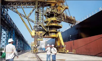  ?? Bloomberg News/PATRICIA MONTEIRO ?? Workers watch as a machine loads soybeans into the Stella Pearl cargo ship headed to China at the Tiplam terminal in Santos, Brazil, in May 2017. A rule change imposed by Brazil’s government in late May pushed freight costs up as much as 150 percent, squeezing farmers’ profit margins.