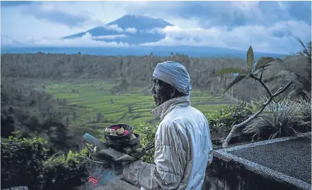  ?? Picture: Getty. ?? A Balinese man prepares for prayer with Mount Agung in the background.
