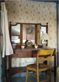  ??  ?? RIGHT A mahogany Sheraton Revival vanity is paired with a thumb-back Windsor chair. The wallpaper is derived from antique block prints.