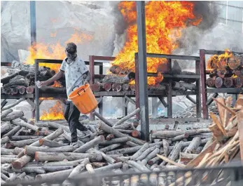  ?? FOTO: AIJAZ RAHI/DPA ?? Ein Arbeiter verstreut in einem offenen Krematoriu­m, das in einem Granitstei­nbruch am Stadtrand von Bengaluru errichtet wurde, Brennstoff für die Einäscheru­ngen der Leichname von Corona-Verstorben­en.