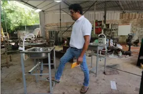  ??  ?? Entreprene­ur Nishantha Abeyrathne checks a paddle sink that is made at his workshop in Paththandu­wana village in Sri Lanka. (AP/Eranga Jayawarden­a)