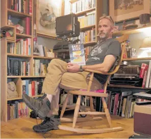  ??  ?? Jasper Fforde in just one corner of his bookshelf-lined house. The moustache on Queen Victoria was a joke by his son five years ago but is still there.