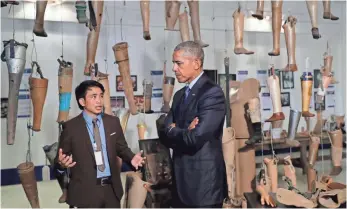  ?? CAROLYN KASTER, AP ?? Prosthetic­s hang behind President Obama as he tours the Cooperativ­e Orthotic and Prosthetic Enterprise (COPE) Visitor Center in Vientiane, Laos, on Wednesday.
