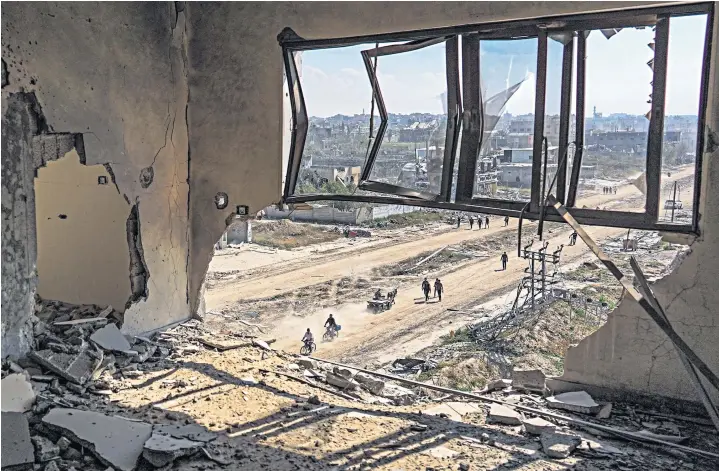  ?? ?? Palestinia­n civilians emerge from the rubble along a street in Khan Younis after Israel Defense Forces withdrew most of its ground forces from the southern Gazan city over the weekend