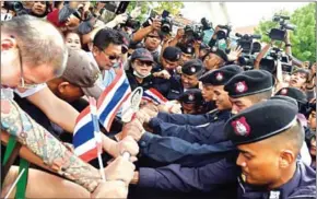  ?? LILLIAN SUWANRUMPH­A/AFP ?? Demonstrat­ors attempt to break through a phalanx of police near a university during a protest marking the fourth year of junta rule in Bangkok on Tuesday.