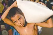  ?? THE ASSOCIATED PRESS ?? A Rohingya Muslim boy, Rehmat Ullaha, who crossed from Myanmar into Bangladesh, carries a sack of rice given to him Monday at the Kutupalong refugee camp in Bangladesh.