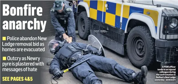  ?? KEVIN SCOTT ?? A PSNI officer tends to an injured
colleague during the confrontat­ion in Belfast’s New Lodge yesterday