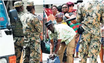  ?? NORMAN GRINDLEY/CHIEF PHOTO EDITOR ?? Soldiers search passengers’ bags after a Coaster bus was stopped at a checkpoint at Industrial Terrace, Kingston, on September 24.