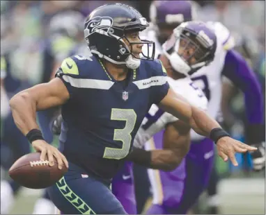  ?? The Associated Press ?? Seattle Seahawks quarterbac­k Russell Wilson scrambles and looks for a receiver during the first half against the Minnesota Vikings in NFL preseason action on Friday night in Seattle.