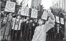  ?? STR / AFP via Getty Images ?? A medical assistance team member takes a selfie Wednesday with Wuhan residents who set up banners of appreciati­on.