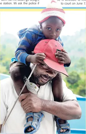  ?? LIONEL ROOKWOOD ?? Little Javier Walker hangs on to his grandfathe­r’s head in Mavis Bank, St Andrew, on Wednesday.