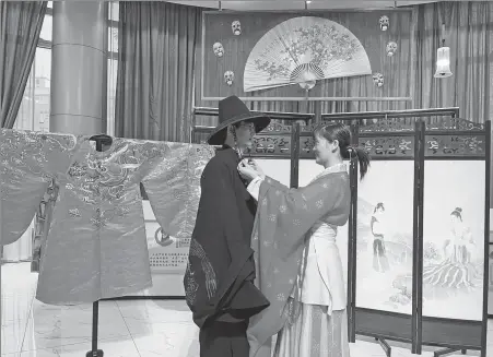  ?? PROVIDED TO CHINA DAILY ?? A staff member (right) of a hanfu company arranges attire for a model in Caoxian county, Shandong province, in 2021.