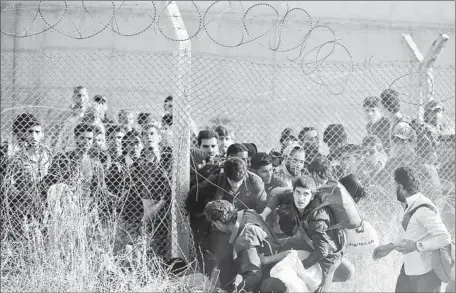  ?? Lefteris Pitarakis
Associated Press ?? SYRIAN REFUGEES breach a border fence to cross into Akcakale, Turkey. Kurdish forces are seeking to capture Tal Abyad, across the border, in Syria. The loss of the town, an entry point for foreign fighters seeking to join Islamic State, would be a...