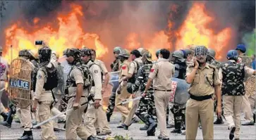  ?? Money Sharma AFP/Getty Images ?? SECURITY FORCES walk by vehicles set alight by rioting followers of a quasi-religious leader in Panchkula. Hundreds of people were injured in the violence, which also involved government buildings set on fire.