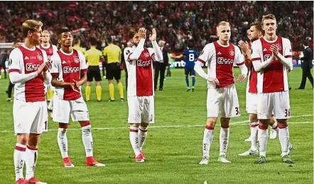  ?? — Reuters / AFP ?? We’re sorry: Ajax Amsterdam players applauding their fans after the 2- 0 loss to Manchester United in the Europa League final in Stockholm on Wednesday. Below: United manager Jose Mourinho being bundled to the ground by his son after the match.