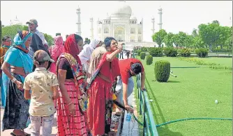  ?? ANI ?? Tourists drinking water from a garden pipe at the Taj Mahal in Agra. An ‘orange alert’ was issued for a severe heatwave in Delhi and neighbouri­ng areas of Punjab, Haryana and Uttar Pradesh, IMD said on Monday.