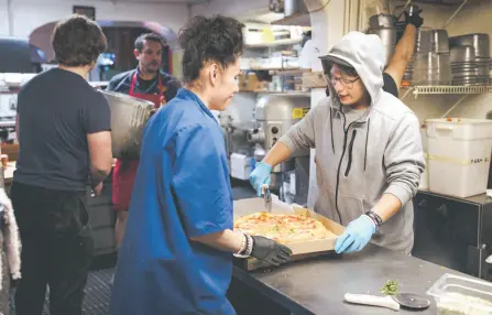  ?? ?? Seventeen-year-old Michael Gallegos (right) prepares an order with Morningsta­r Jamón (centre) at Old Town Pizza in Albuquerqu­e.