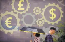  ?? AP PHOTO/MARK SCHIEFELBE­IN ?? People walk past a mural displaying world currency symbols on the outside of a bank July 20 in Beijing. Amid a worsening tariff battle, China is putting off accepting license applicatio­ns from American companies in financial services and other industries until Washington makes progress toward a settlement, an official of a business group said Tuesday.