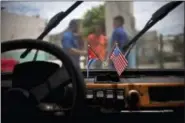  ?? RAMON ESPINOSA — THE ASSOCIATED PRESS FILE ?? In this file photo a Cuban and a U.S. flag hang on the windshield of a car in a garage in Havana, Cuba. Diplomats say the U.S. is expected to abstain, for the first time, from a U.N. resolution criticizin­g America’s economic embargo against Cuba. Such...