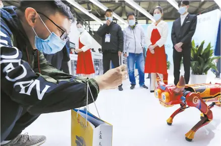  ??  ?? A visitor takes pictures of a robot decorated as an ox at the telecommun­ications show, MWC Shanghai 2021, which opened yesterday. More than 200 exhibitors are attending the show. — Xinhua